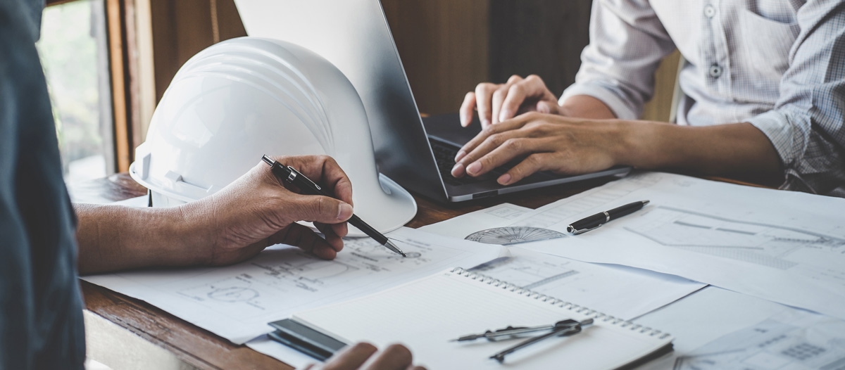 Two people reviewing construction blueprints at a desk in Carlsbad.